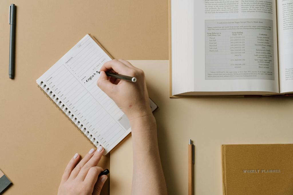 Persona planificando sus nuevos hábitos en una agenda sobre un escritorio organizado, como estrategia para construir el éxito de forma consciente.